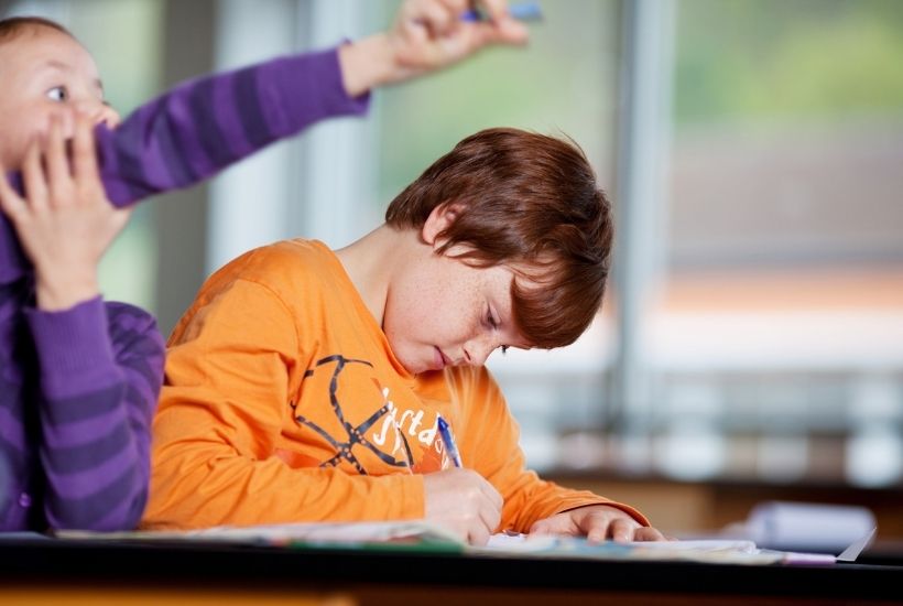 Young male student writing on a piece of paper