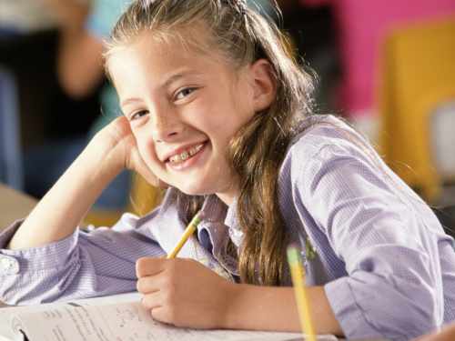 Smiling homeschool girl working in a workbook.